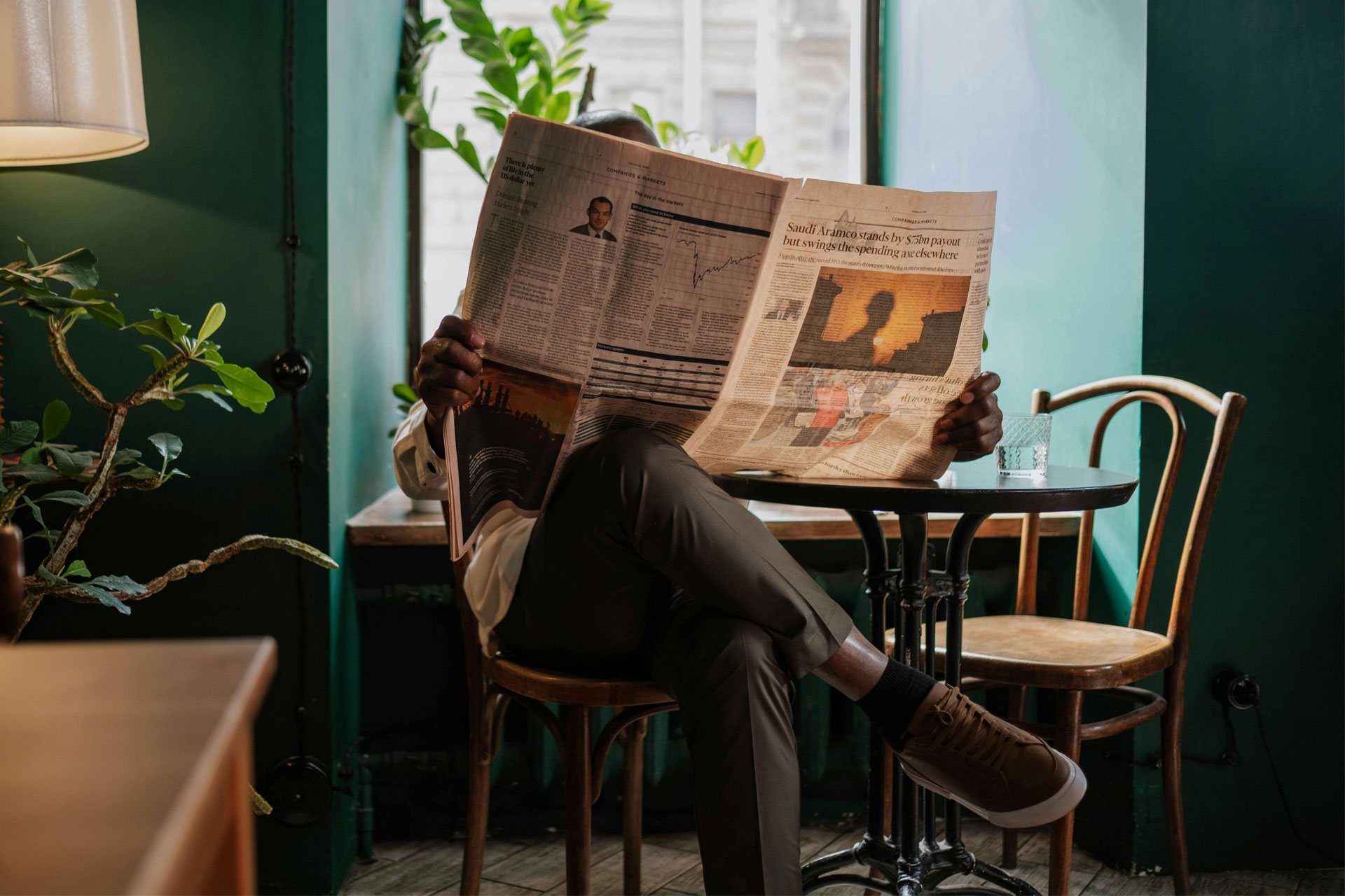 Ein Mensch in einem Café, Zeitung lesend